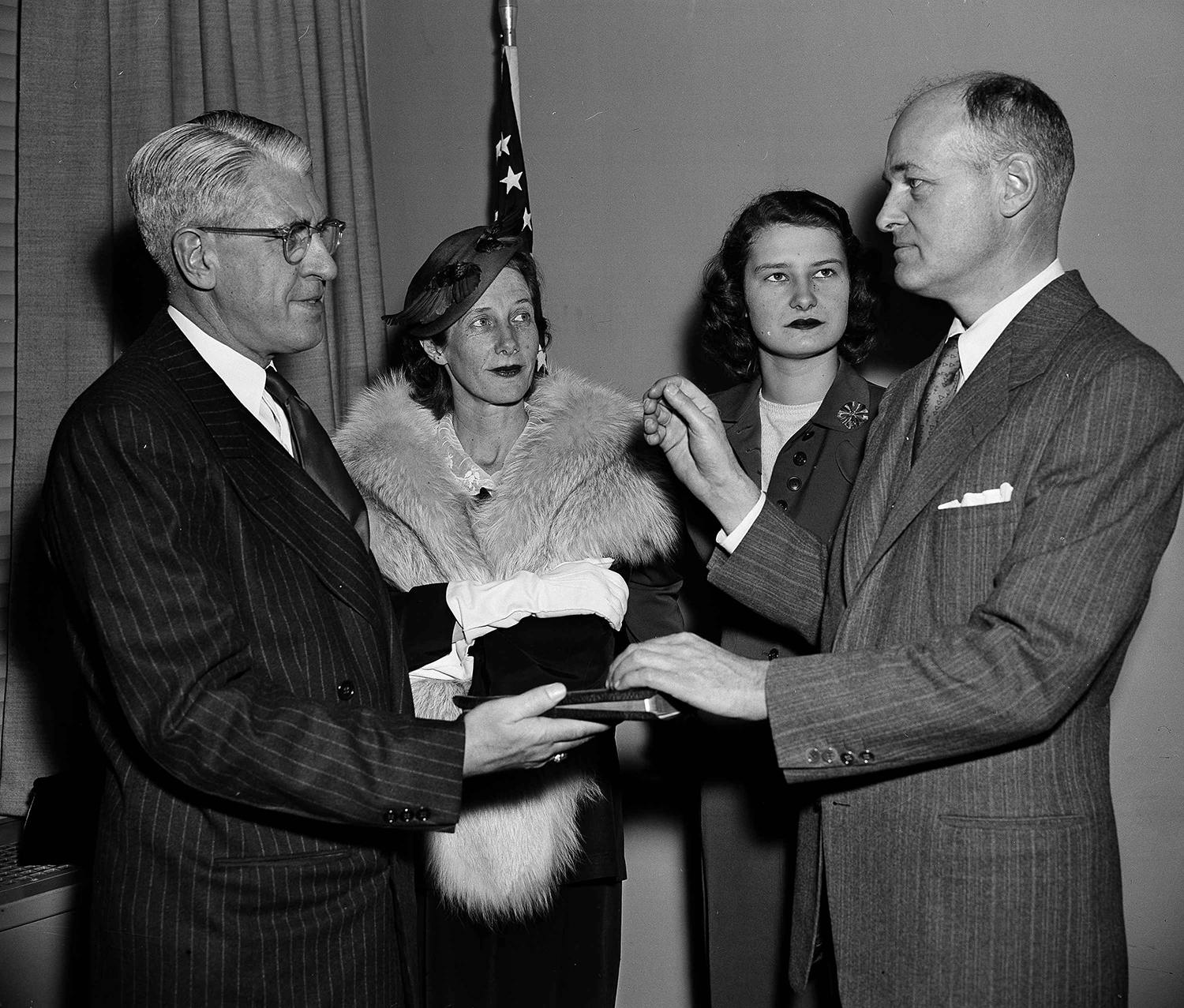 George F. Kennan becomes Ambassador to the Soviet Union in a State Department ceremony April 2, 1952. Kennan, left, reenacts the swearing in by Raymond Muir, protocol officer, with Mrs. Kennan (second from left), and daughter Grace, 19, looking on. (AP Photo/Byron Rollins)