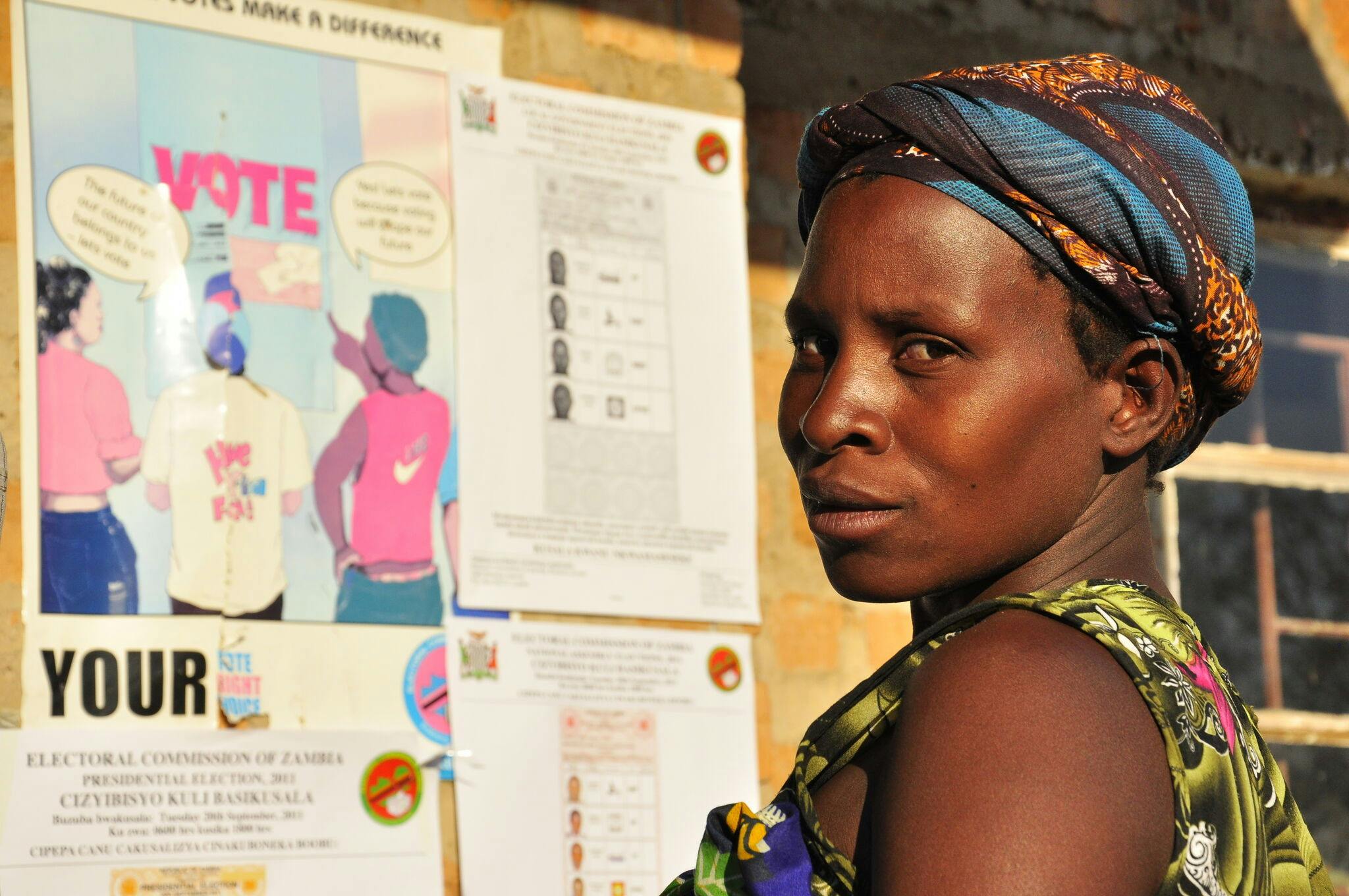 A woman in front of a voting poster