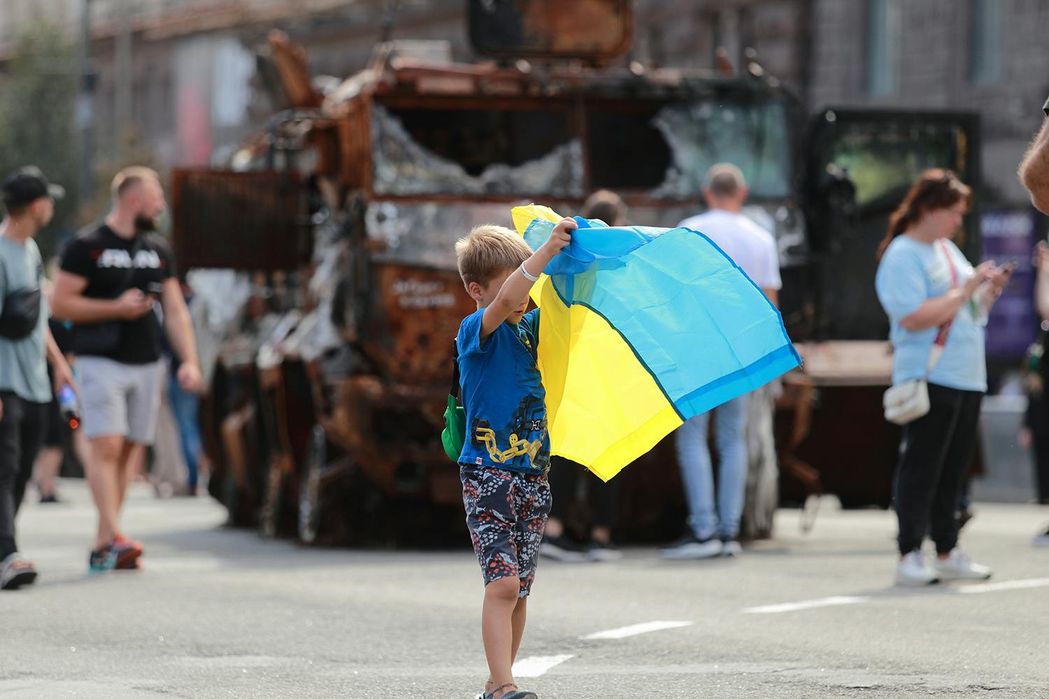 Child unfolds the Ukrainian flag against the background of a broken tank during Ukraine Independence Day parade, which coincided with the six-month mark of Russia’s invasion. 